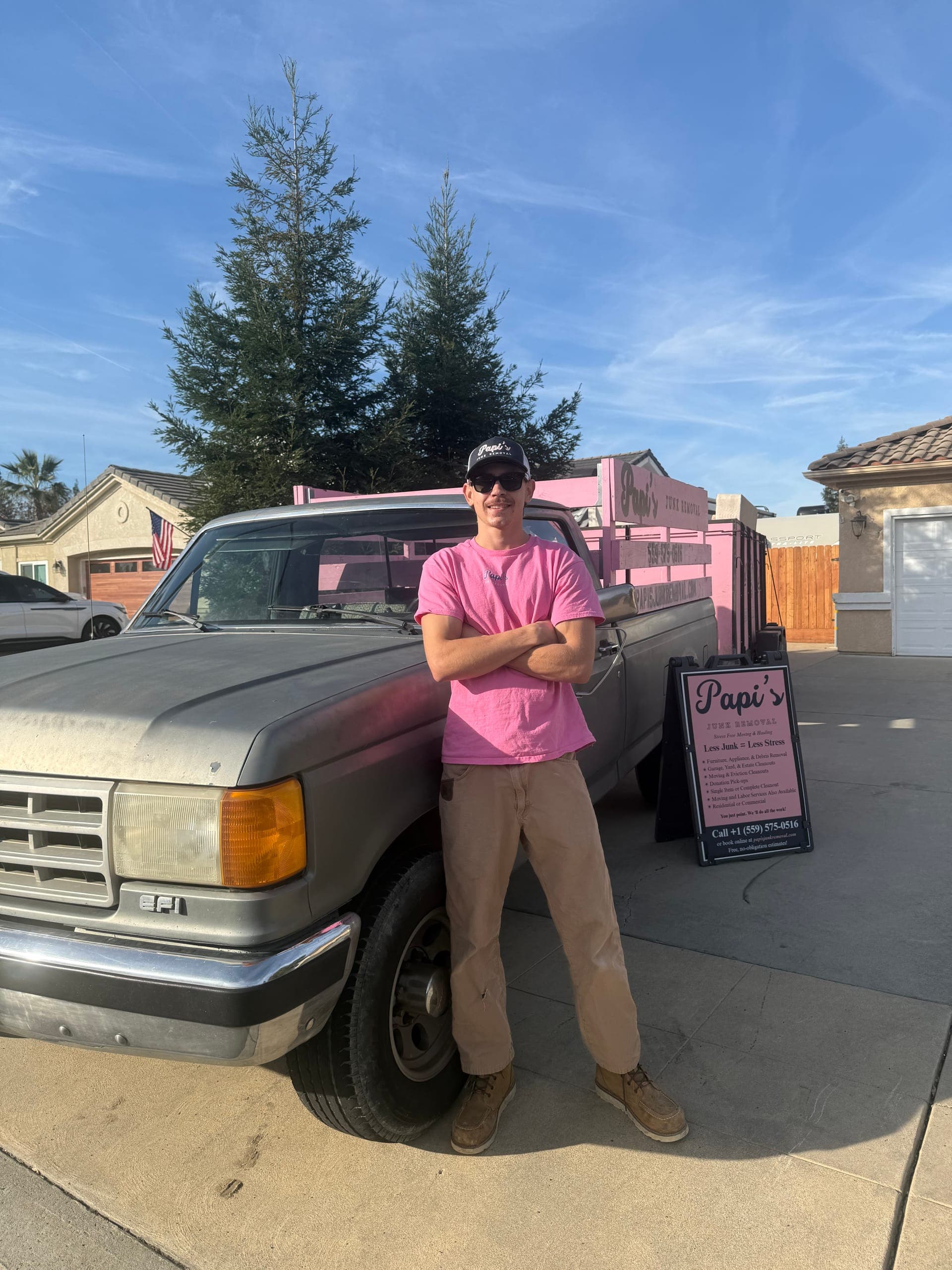 Papi's crew member by the pink-rack Ford and Papi's yard sign, ready to give a quote