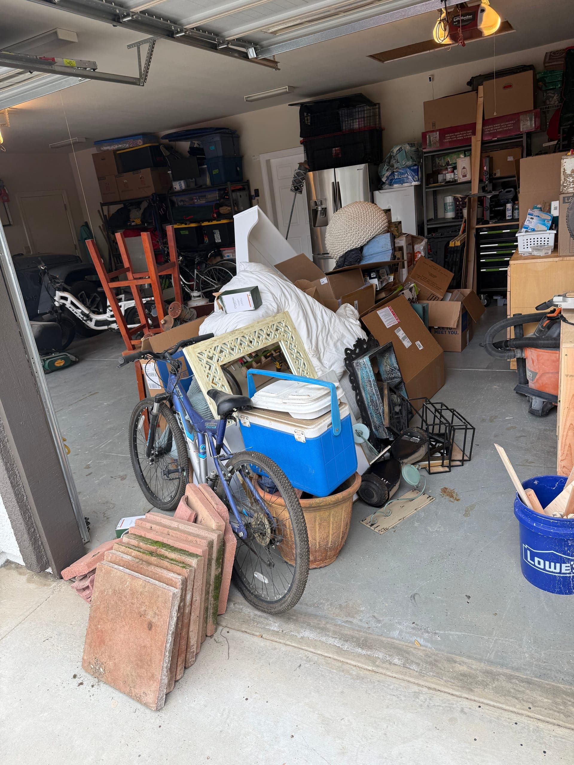 Two-car garage blocked by boxes, a bike, a cooler and pavers before a Papi's garage cleanout